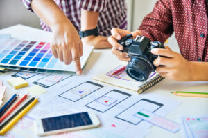 Designers planning website layout with camera, color palette, and UX sketches for visual content strategy