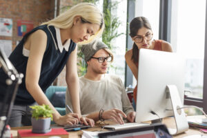 Marketing team collaborating at computer to repurpose content for multiple platforms